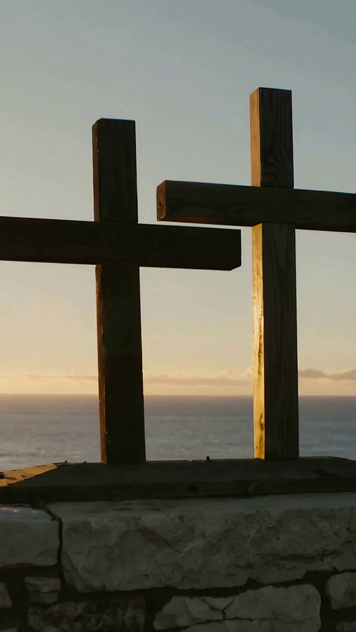 Video verticale: Il sole che tramonta riscalda due croci di legno su una sporgenza di scogliera, creando un breve bagliore dell'obiettivo.