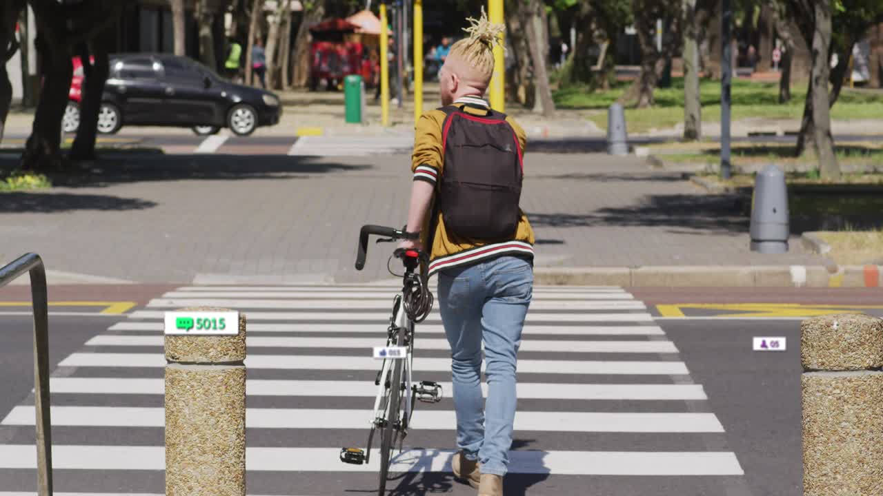 Animasjon av varslingslinjer over en albino afroamerikansk mann som krysser gaten med sykkel.