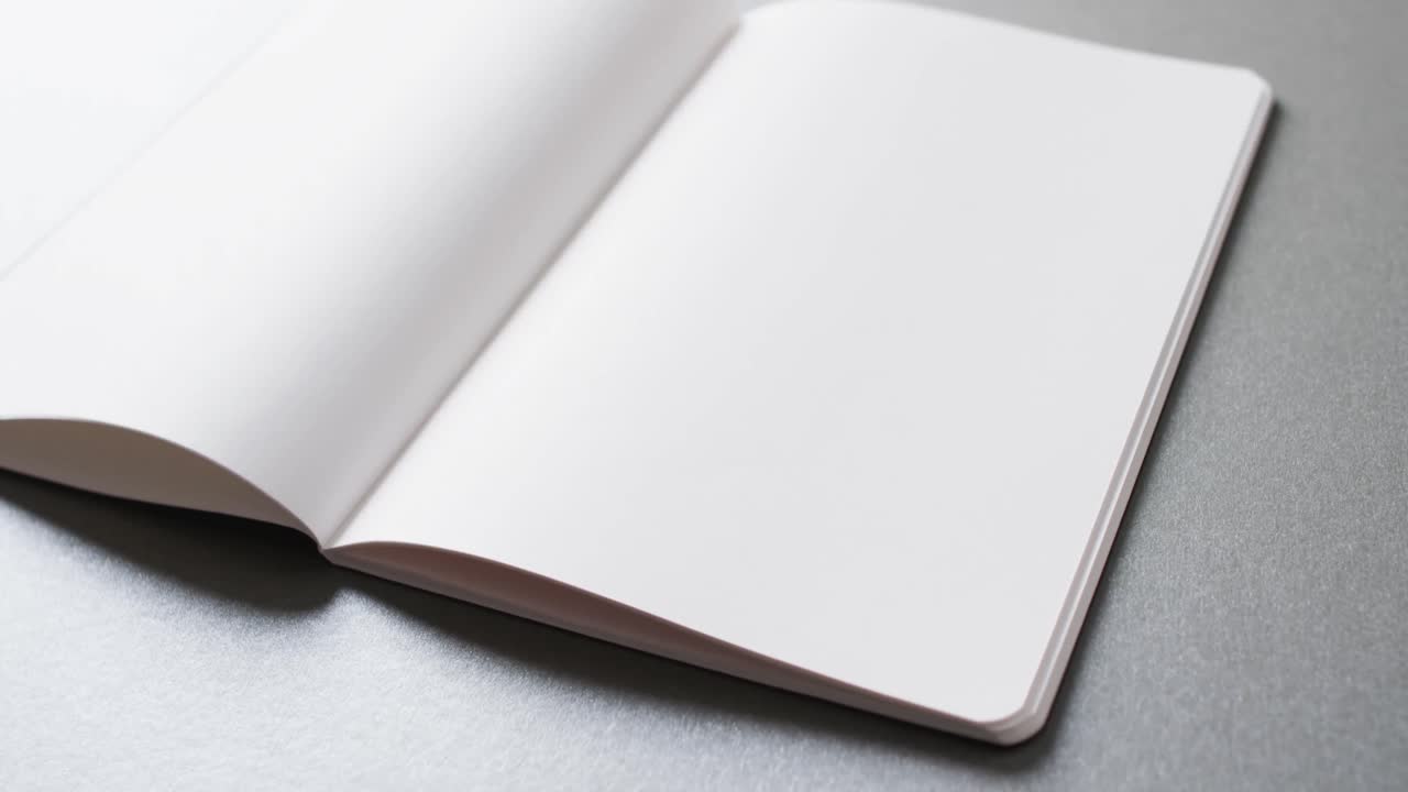 Close up of open blank book with copy space on gray background in slow motion