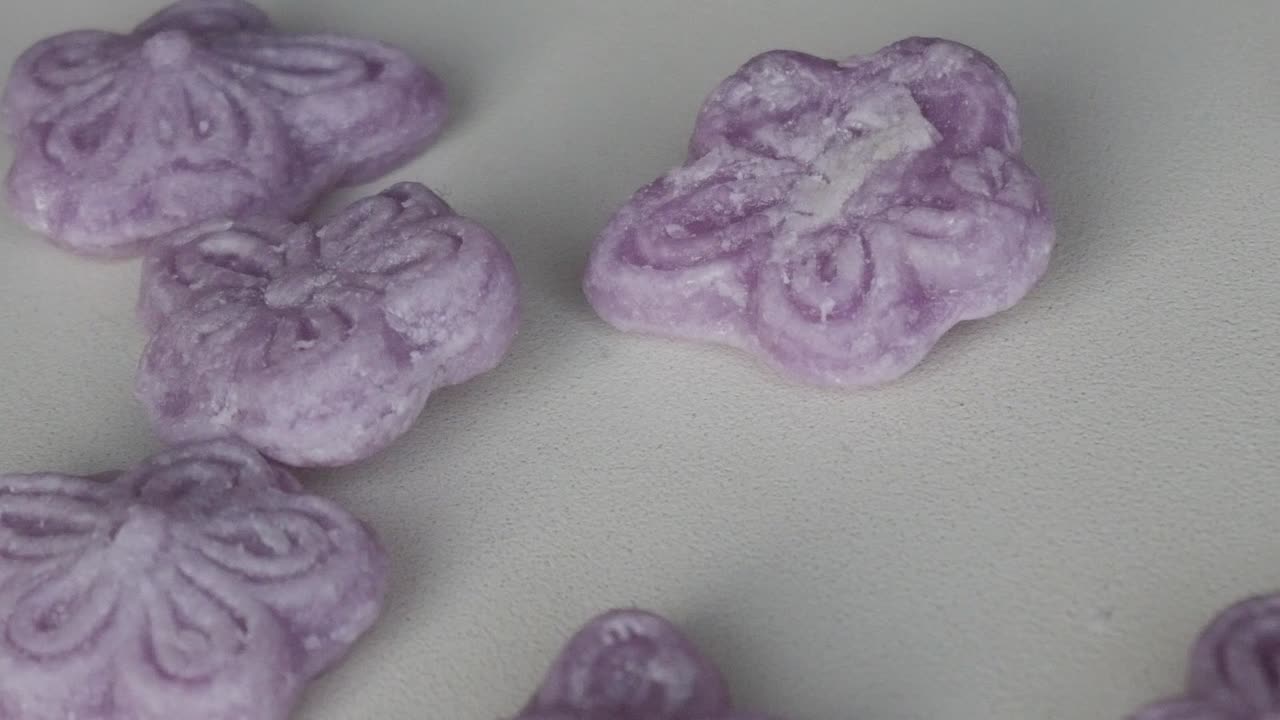 Close-up of violet candies with intricate patterns on a white surface