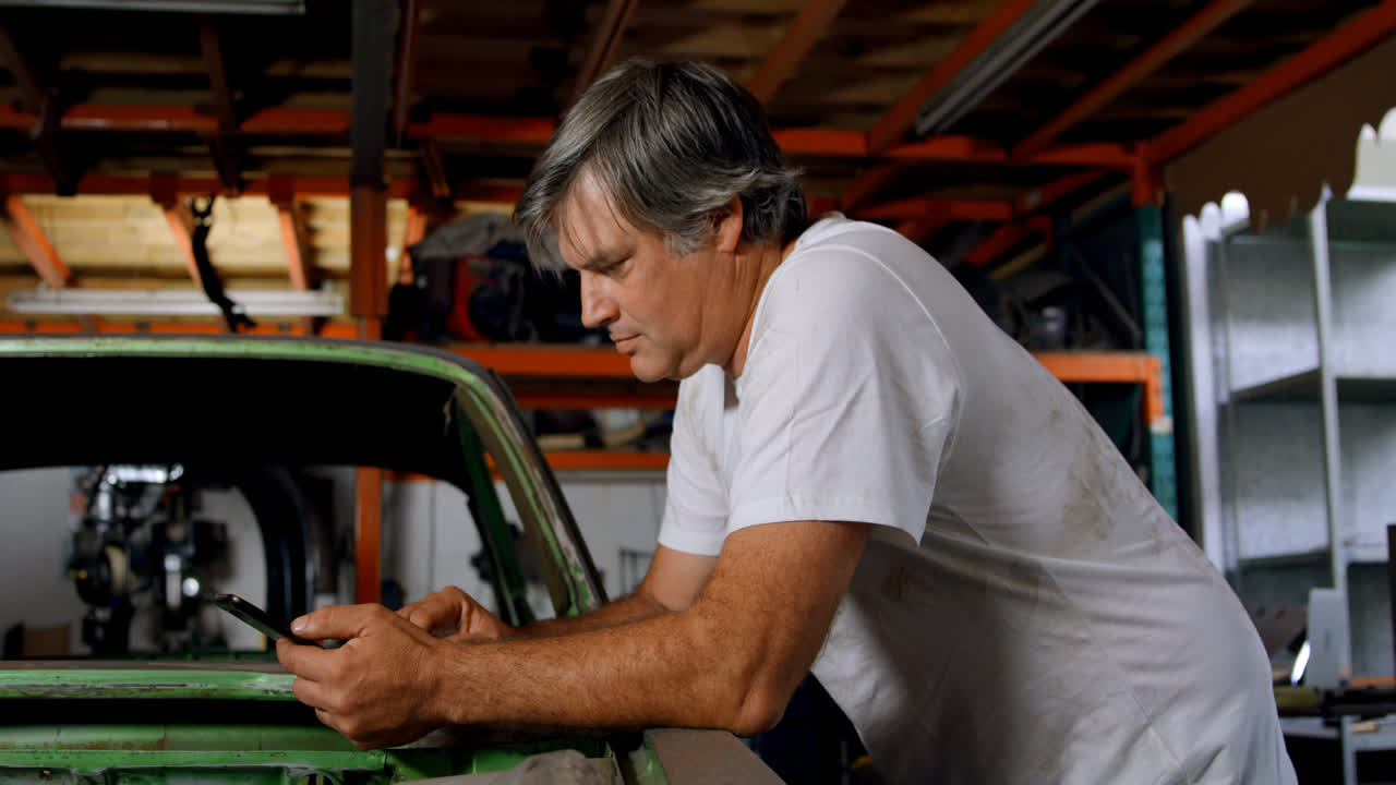mecánico masculino usando el teléfono móvil 4k