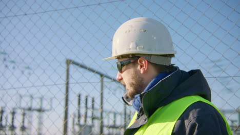 Male-engineer-speaking-over-the-walkie-talkie-then-looks-around-then-starts-talking-again,-closeup-slow-motion