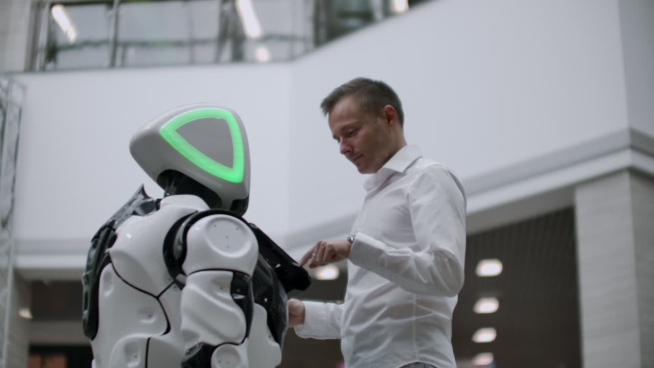 el hombre en el centro comercial se comunica con un asesor robot. tienda moderna y vendedor robot. robot ayuda a un hombre en el centro comercial.