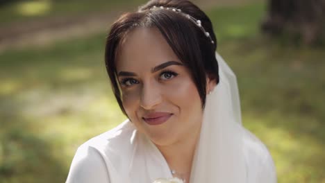novia en vestido de boudoir sentada en el jardín de la mañana con un ramo de rosas, mujer en vestido de noche velo