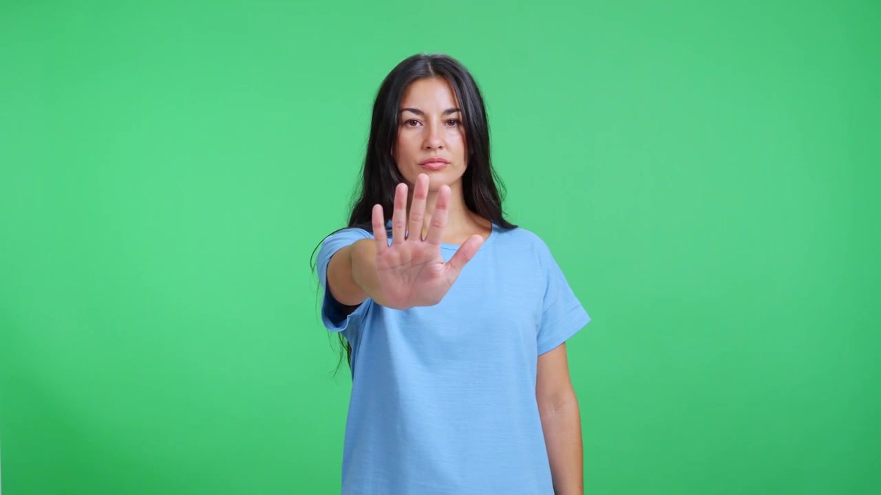 Young Woman Making a Stop Gesture Against a Green Screen