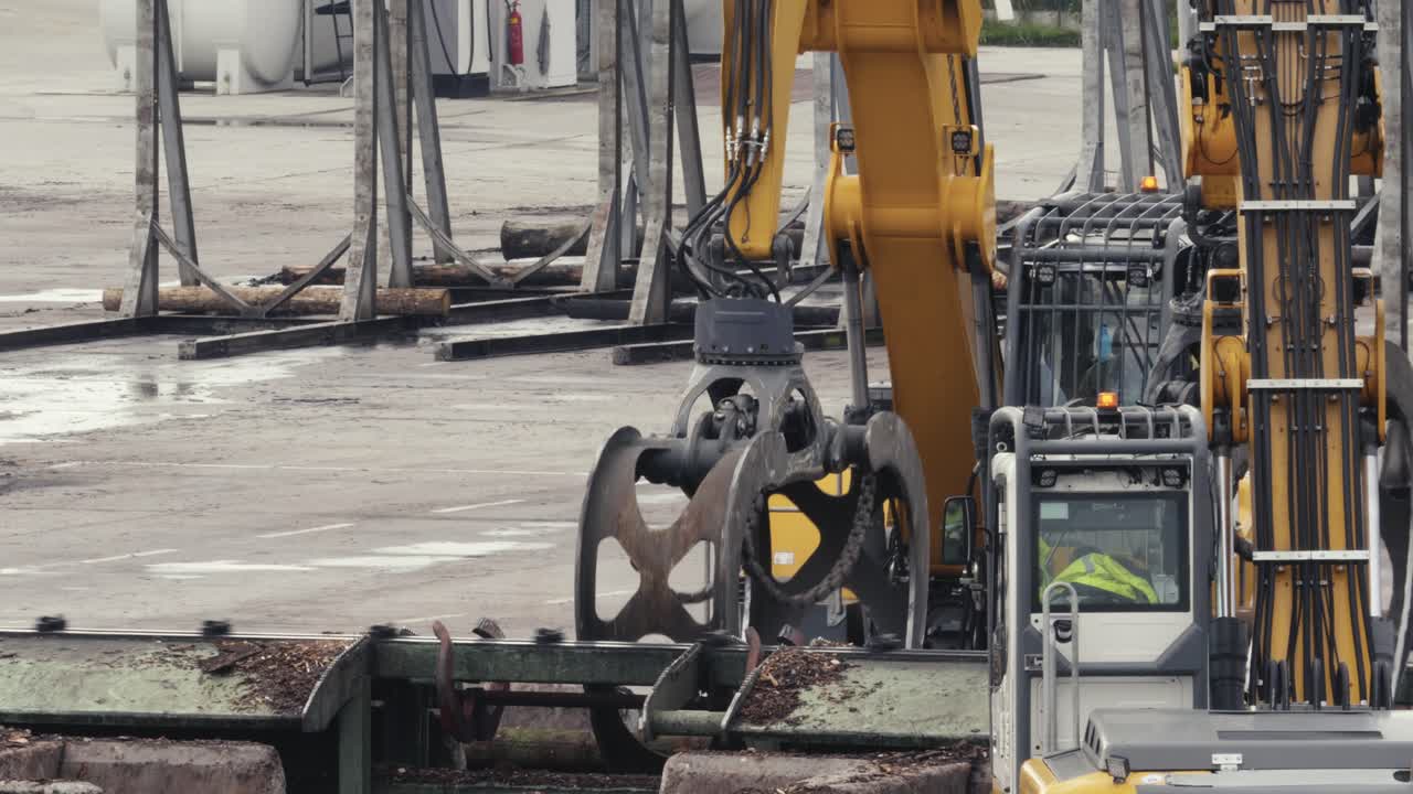 중장비가 컨베이어 벨트에서 떨어지는 통나무를 집어들다