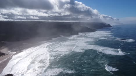 beautiful amado beach near sagres in south portugal with nice waves and sunn weather, some fog under the clouds