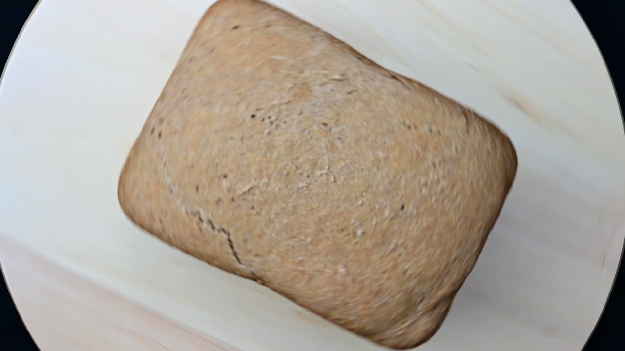 Freshly baked rye bread rotates on a wooden board