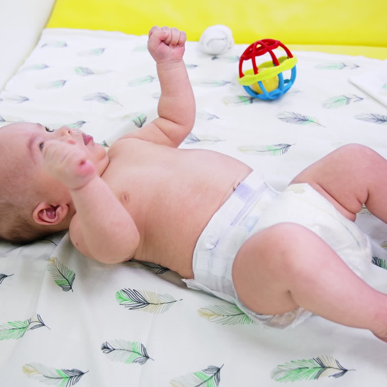 Pediatrician is holding baby's foot in her hands and turning it to check. Toddler at the surgeon's examination. Side view