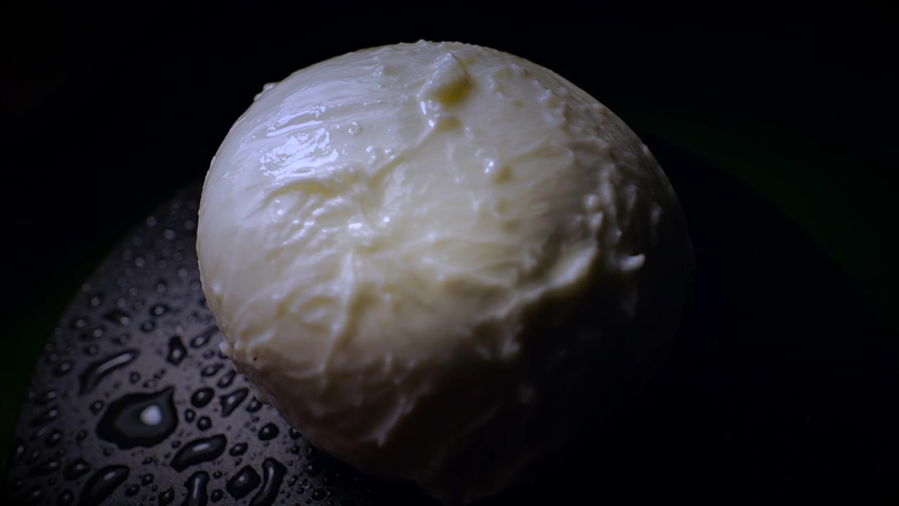 Primo piano di mozzarella fresca che ruota per rivelare una consistenza cremosa.