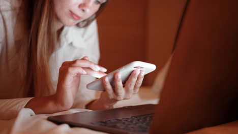 mujer usando teléfono y portátil por la noche