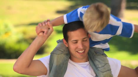 young boy playing on his fathers shoulders