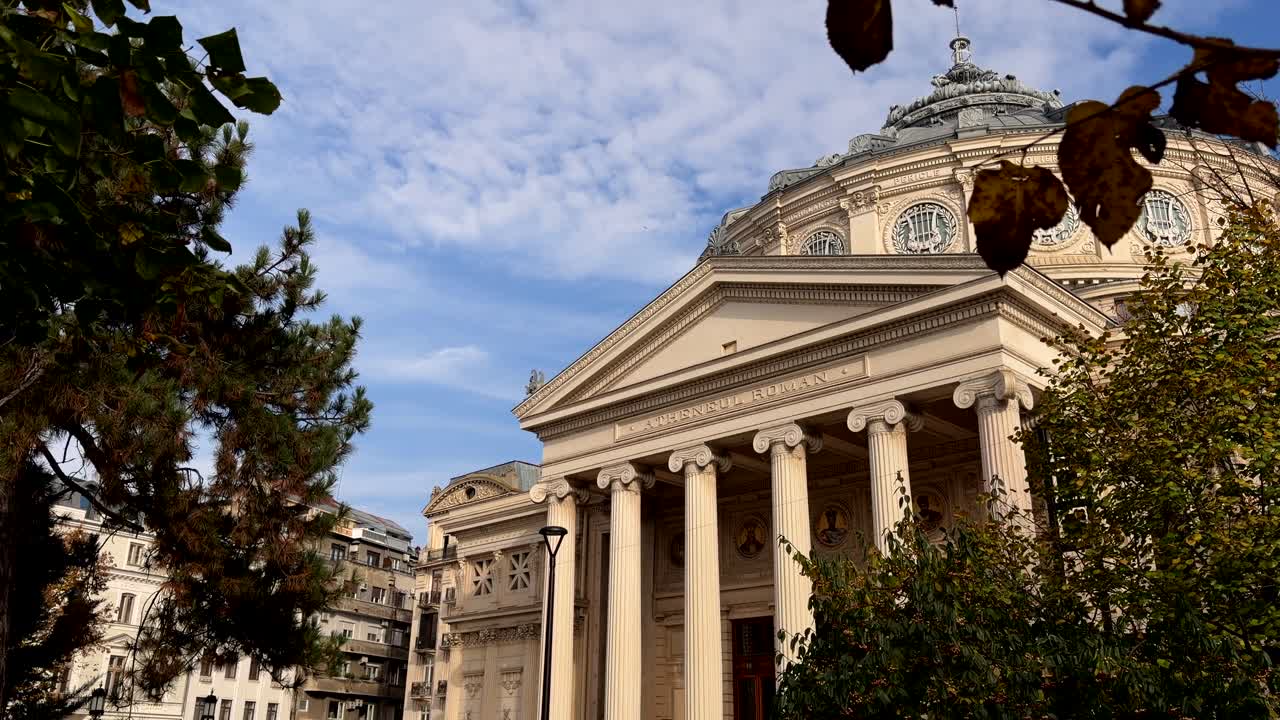 햇빛 속 루마니아 아테네움 외관과 주변의 푸른 녹지