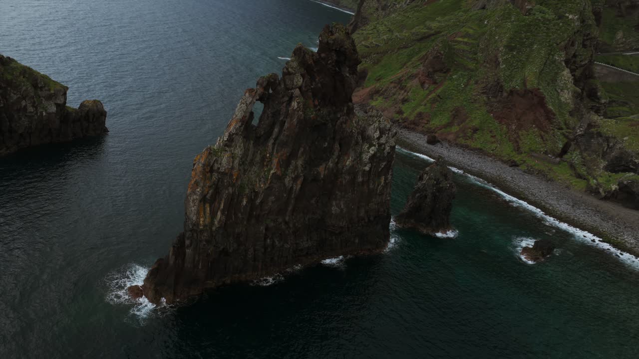 Drone orbits iconic Ilhéus da Ribeira da Janela sea stacks, volcanic coastline, Madeira, Portugal. Aerial drone top-down view