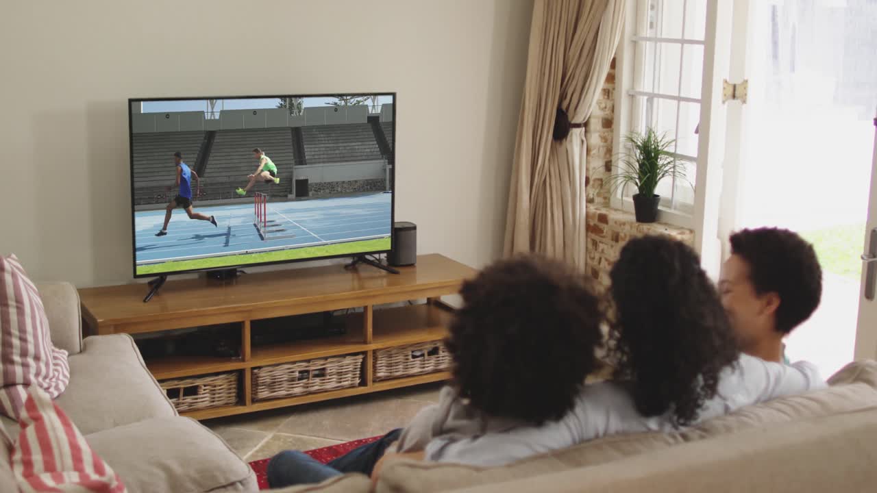 Composizione di famiglia felice seduta insieme a casa che guarda un evento di atletica leggera di corsa in TV.