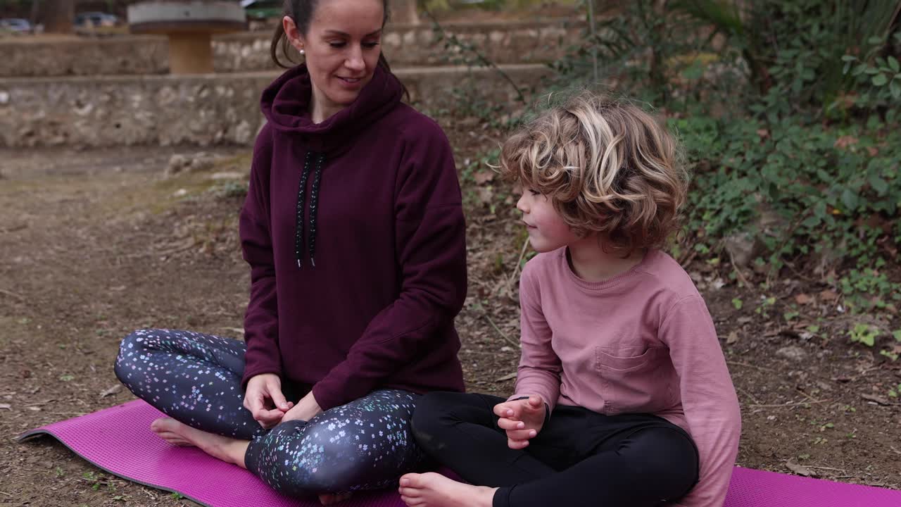 madre con su hijo meditando en un tapete de yoga en el parque