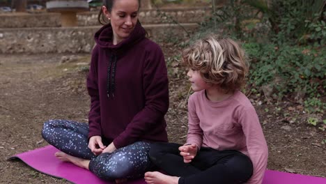 mother with son meditating on yoga mat in park