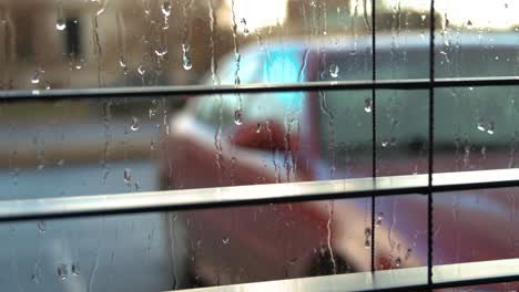 slow pan from left to right through window blinds at a car in the rain outside