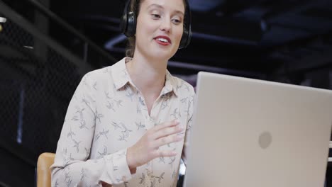 Feliz-Mujer-De-Negocios-Caucásica-Casual-Haciendo-Videollamadas-Usando-Una-Computadora-Portátil-En-El-Salón-De-La-Oficina,-Cámara-Lenta