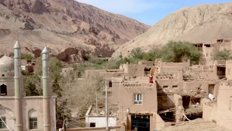 young woman in red dress walking on mud house rooftop in tuyoq rural chinese village