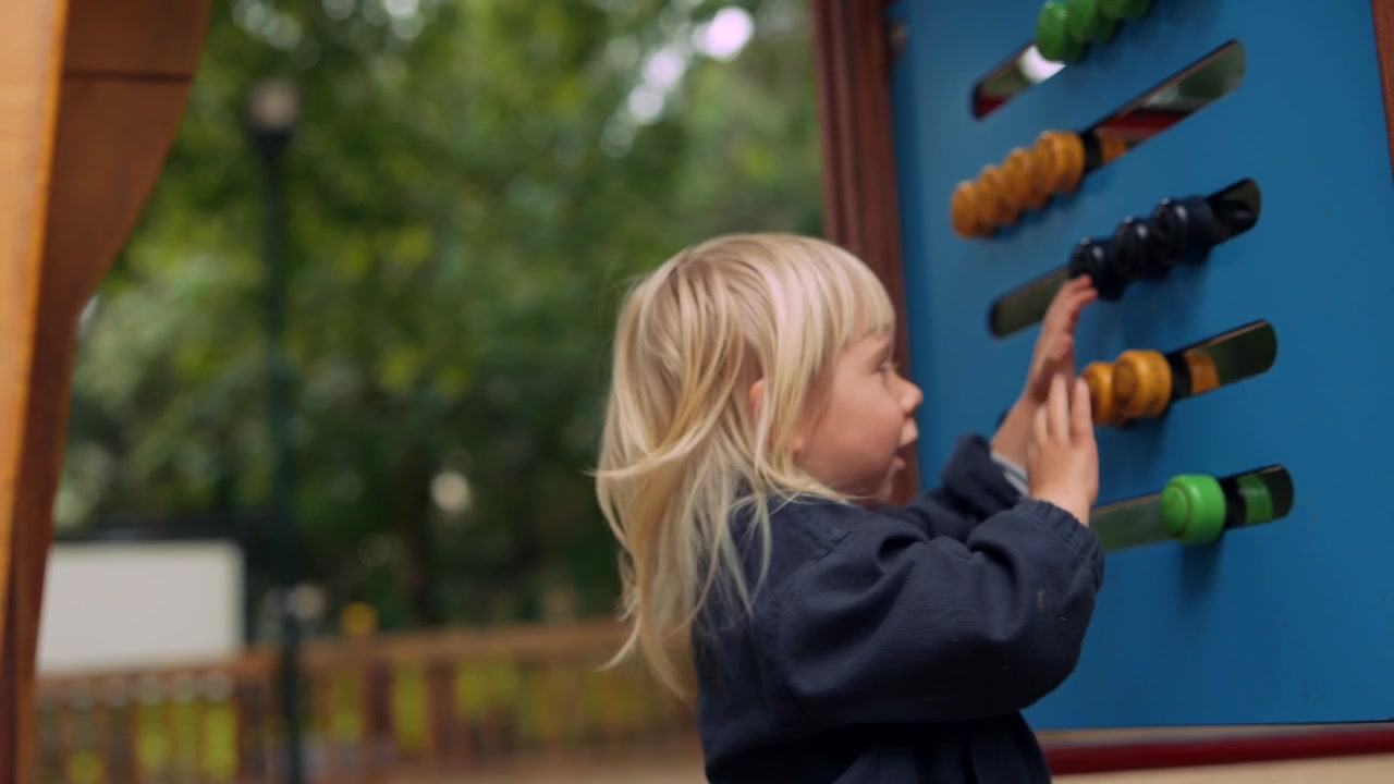 Blonde Toddler Playing with Colorful Abacus Toy on Playground