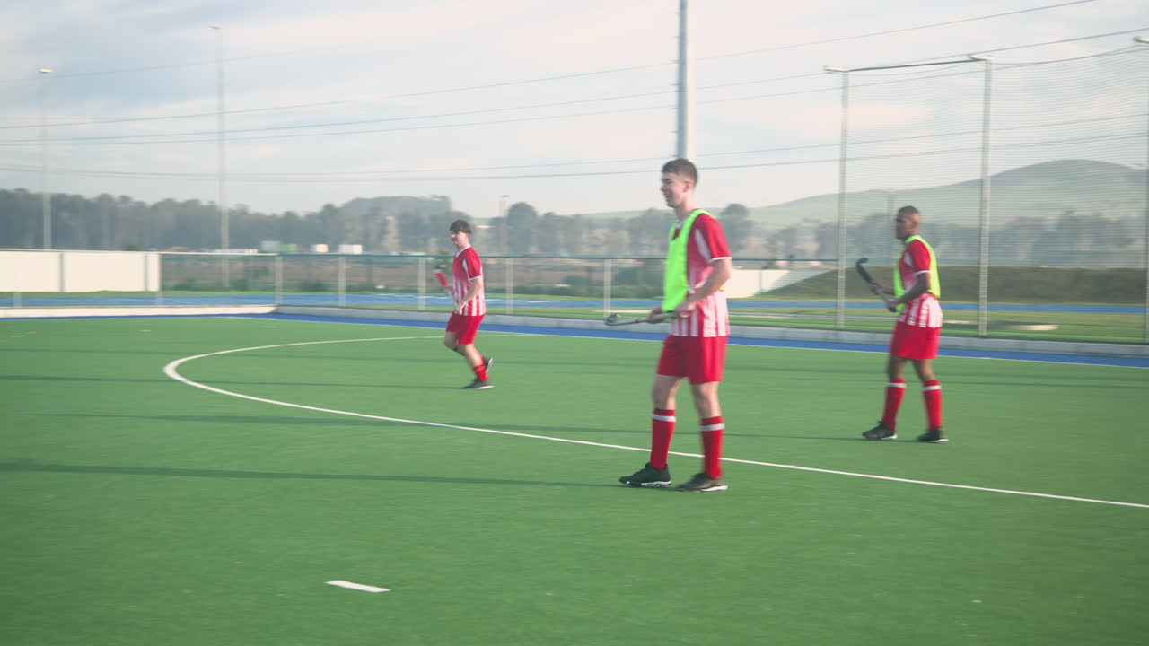 Playing field hockey, men competing intensely on outdoor sports field