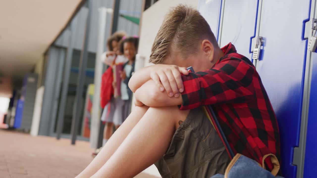 Video of sad caucasian schoolboy being taunted by two diverse children at school