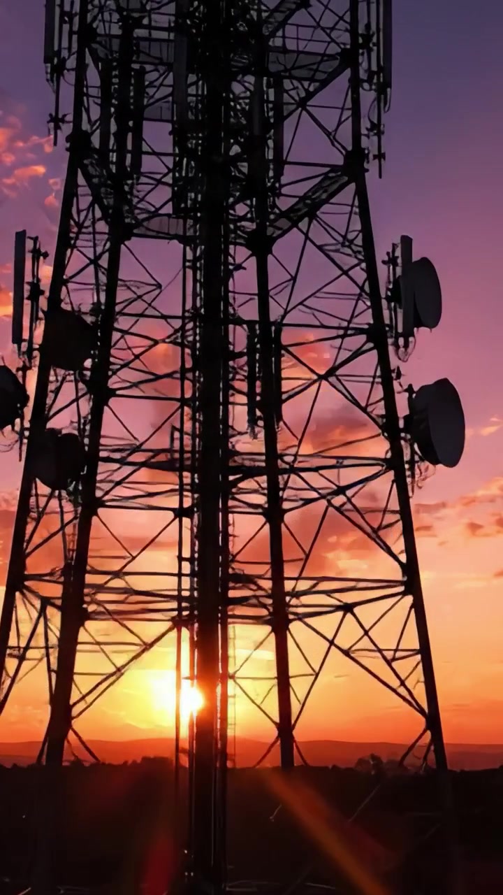 Silhueta Cativante de uma Torre de Telecomunicações Contra um Céu Deslumbrante ao Pôr do Sol com Cores Vibrantes de Laranja e Roxo Iluminando o Horizonte Noturno