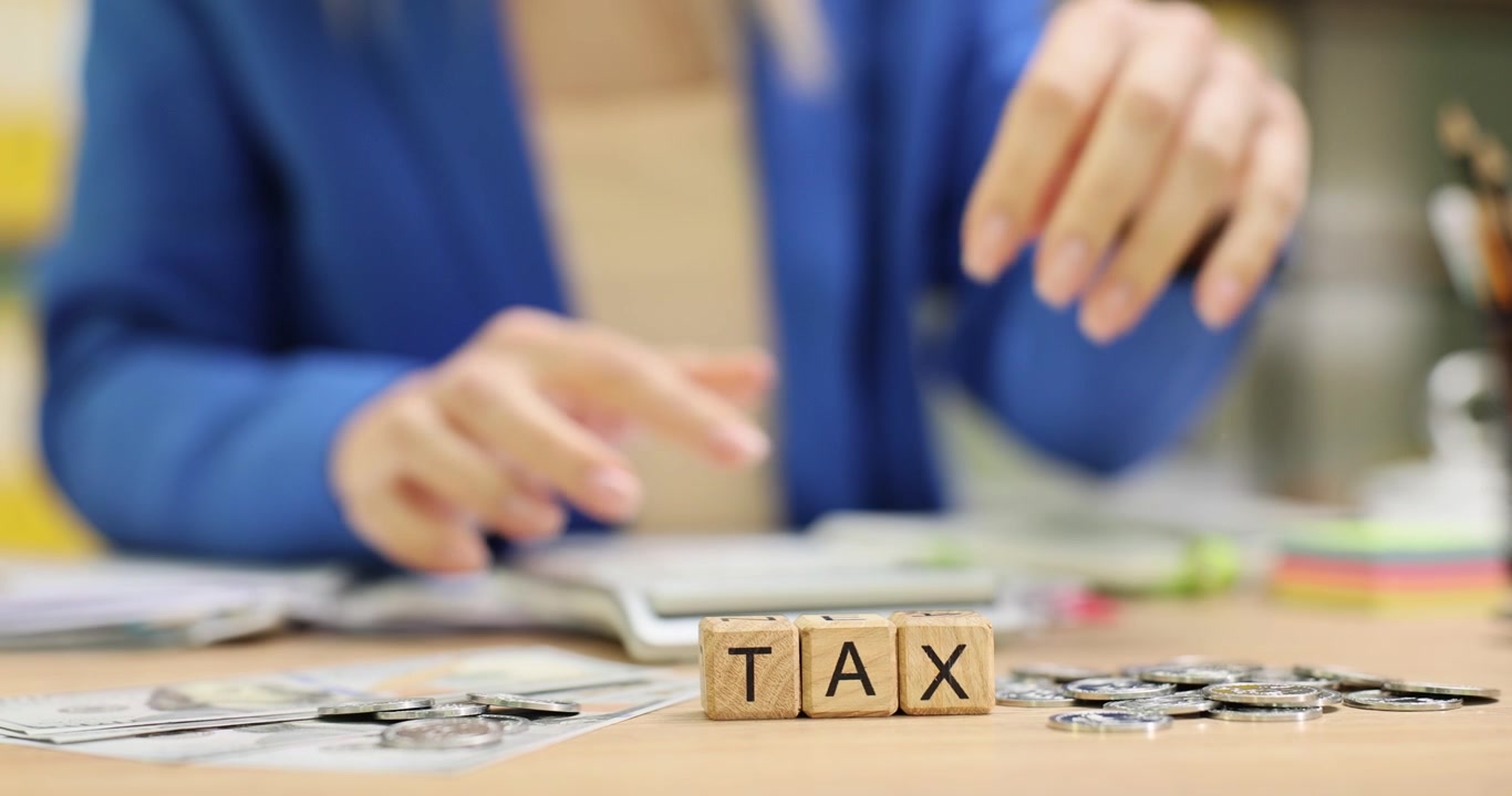 Word tax from wooden cubes against woman throwing coins