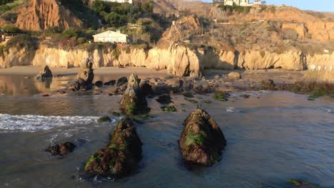 Vista-Aérea-De-Las-Olas-Rodando-Hacia-La-Orilla-En-La-Playa-El-Matador-Durante-La-Hora-Dorada,-Malibu-California