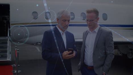 red de conexiones contra dos hombres de negocios caucásicos discutiendo juntos en el aeropuerto