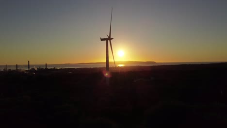 establisher static shot of silhouetted wind turbine turning against sunset