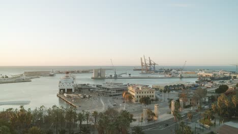 wide shot showing industrial harbor and port of malaga with cranes and shipyard during sunrise