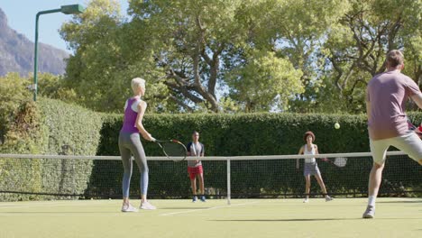 happy diverse group of friends playing tennis at tennis court