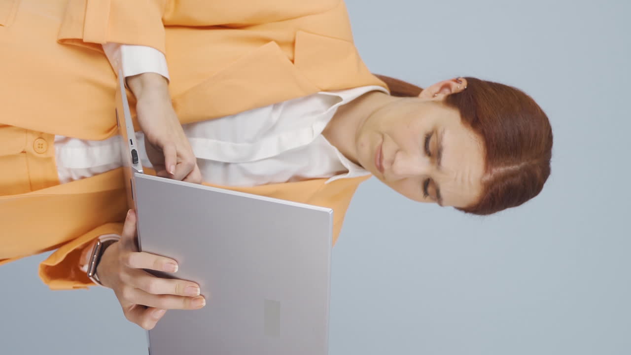 video vertical de una mujer de negocios mirando una computadora portátil con una expresión cansada.