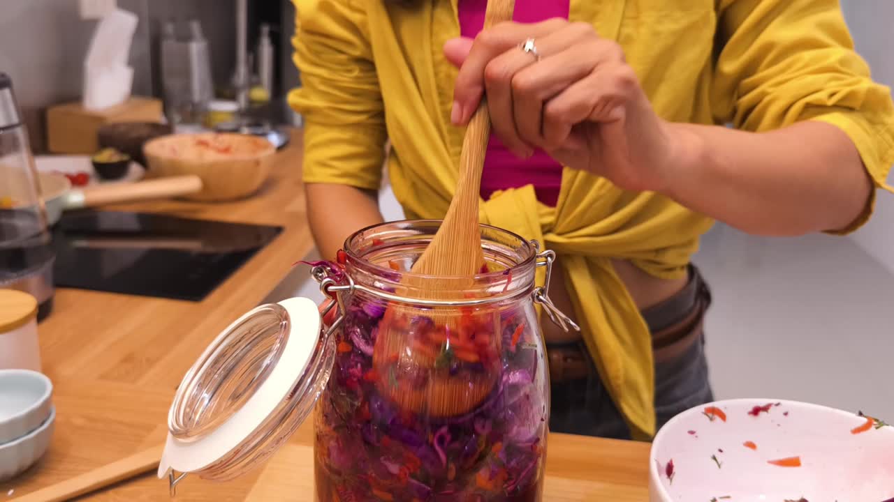 mujer haciendo repollo rojo fermentado en un frasco de vidrio