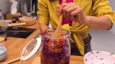 woman making fermented red cabbage in a glass jar