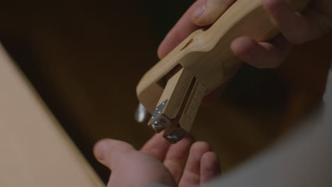 a detailed shot of hands adjusting a wooden leather crafting tool featuring a precision scale, used for measuring and cutting leather with accuracy.