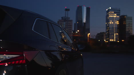 man putting a charger in an ev car and going to night work in a business center