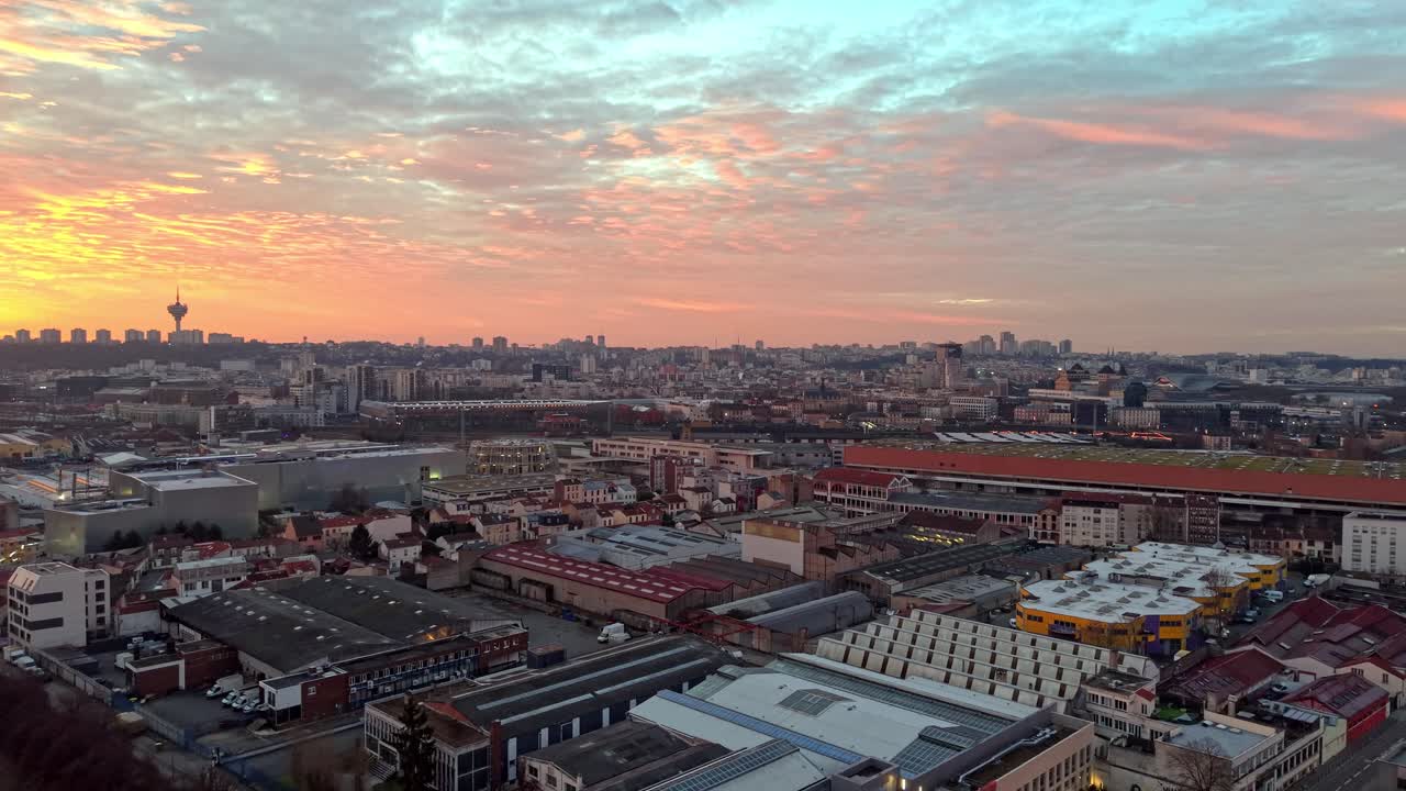 Aerial drone view of Parisian cityscape at golden hour sunset with dramatic colorful sky, urban buildings and landmarks visible across metropolitan area, Paris, France