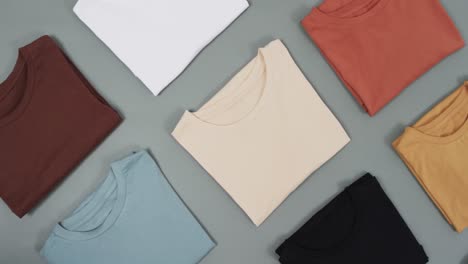 video of flat lay of t shirts with copy space on grey background