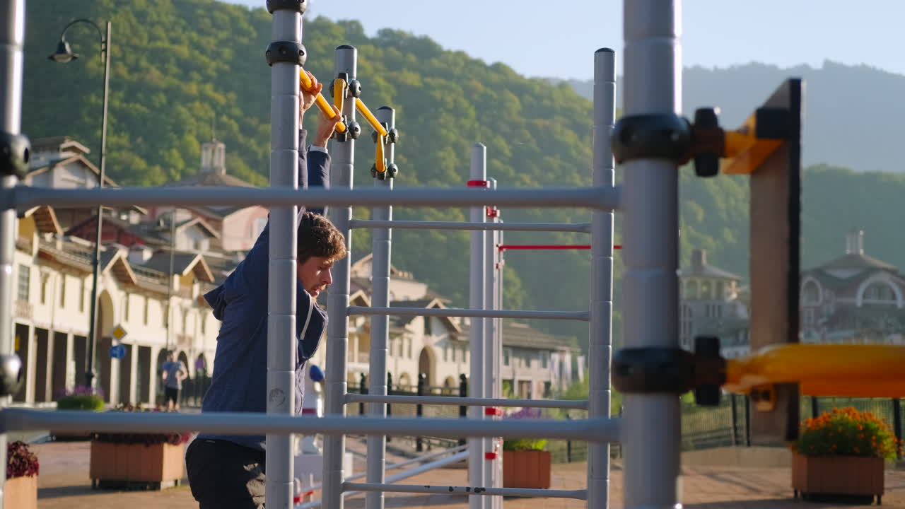 남자 는 공원 에서 풀업 을 하고 칼리스테닉 바 에 매달려 있다