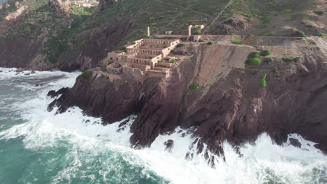 aerial view in orbit of the abandoned nebida mine in sardinia and being seen in strong sea waves on the coast