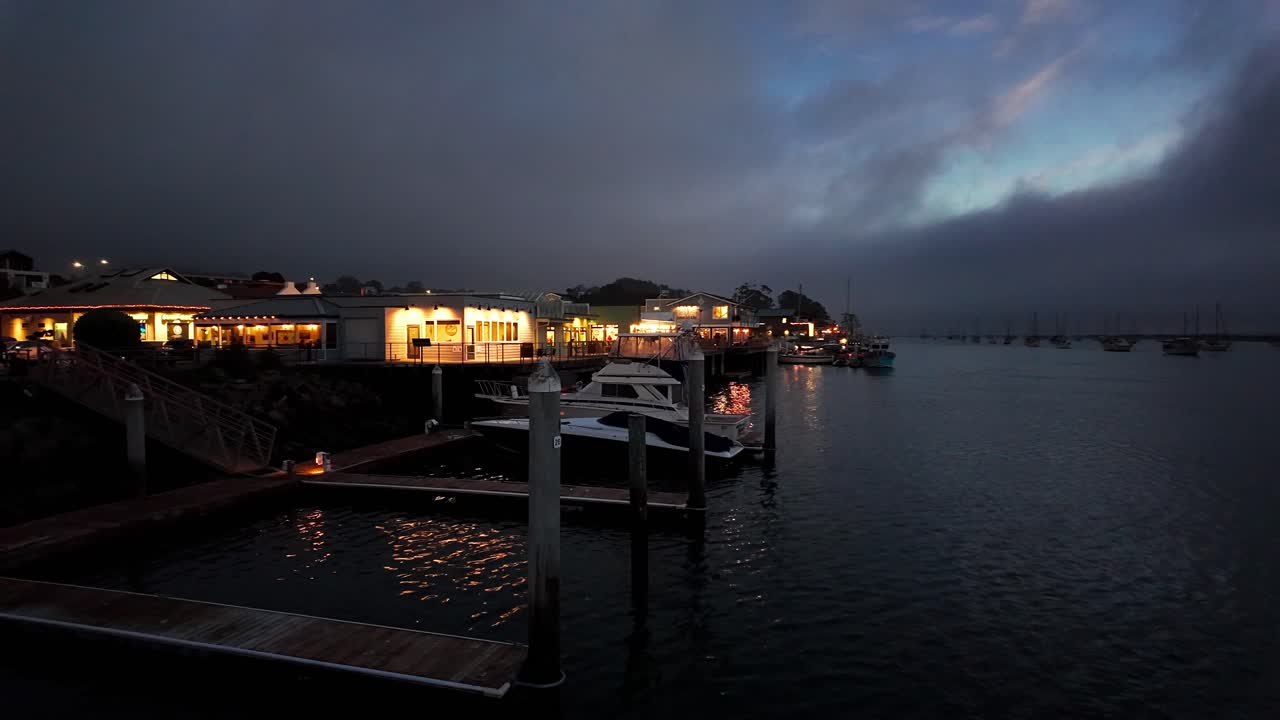 Gimbal wide panning shot of the charming Embarcadero commercial district on the waterfront in Morro Bay, California at night. 4K