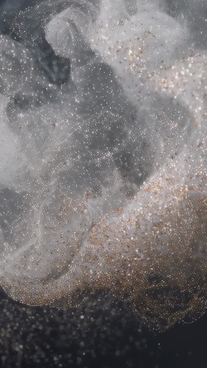 Video verticale: nuvola sottile che si disperde in liquido scuro, flusso fluido che sposta i glitter verso il basso