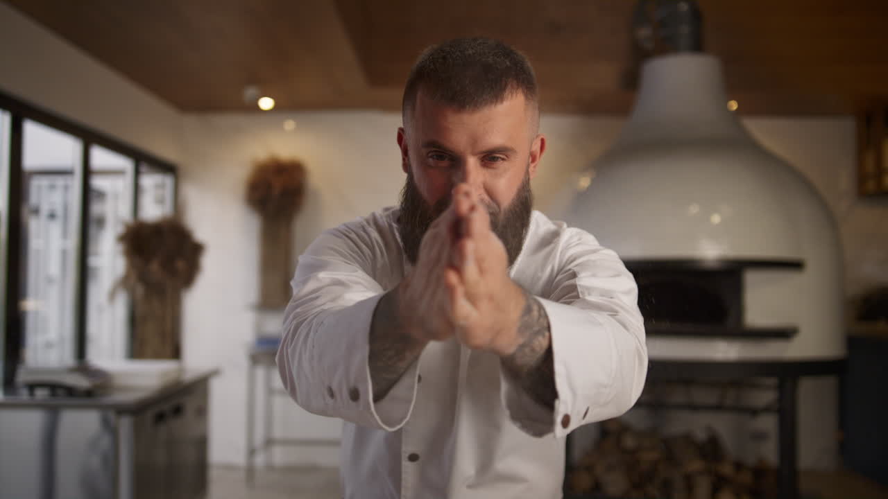 hombre guapo cocinero de panadería en la cocina. manos de panadero tamizando harina en la cafetería.