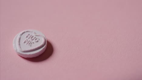 hand picking up heart candy with romantic message hug me on pink background