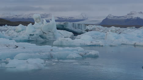 Glacier-Lagoon,-Jökulsárlón,-Iceland,-with-icebergs-and-flowing-icy-blue-water