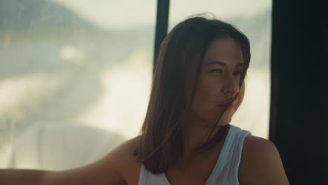 dreaming woman with messy hair rides motorboat at sea cruise. calm lady sits in salon of sailing yacht on summer vacation. passenger on boat board