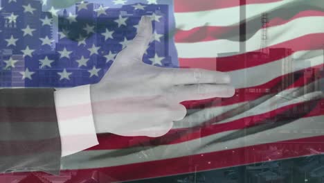 animation of hand of smart caucasian making gun gesture over waving american flag and city buildings